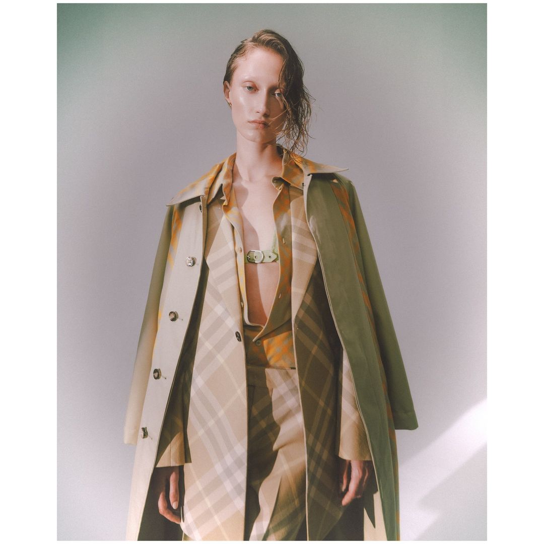 Model wearing a patterned beige coat and matching shirt against a light grey studio background.