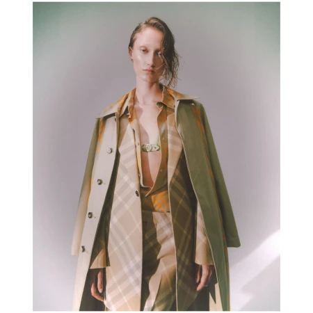 Model wearing a patterned beige coat and matching shirt against a light grey studio background.