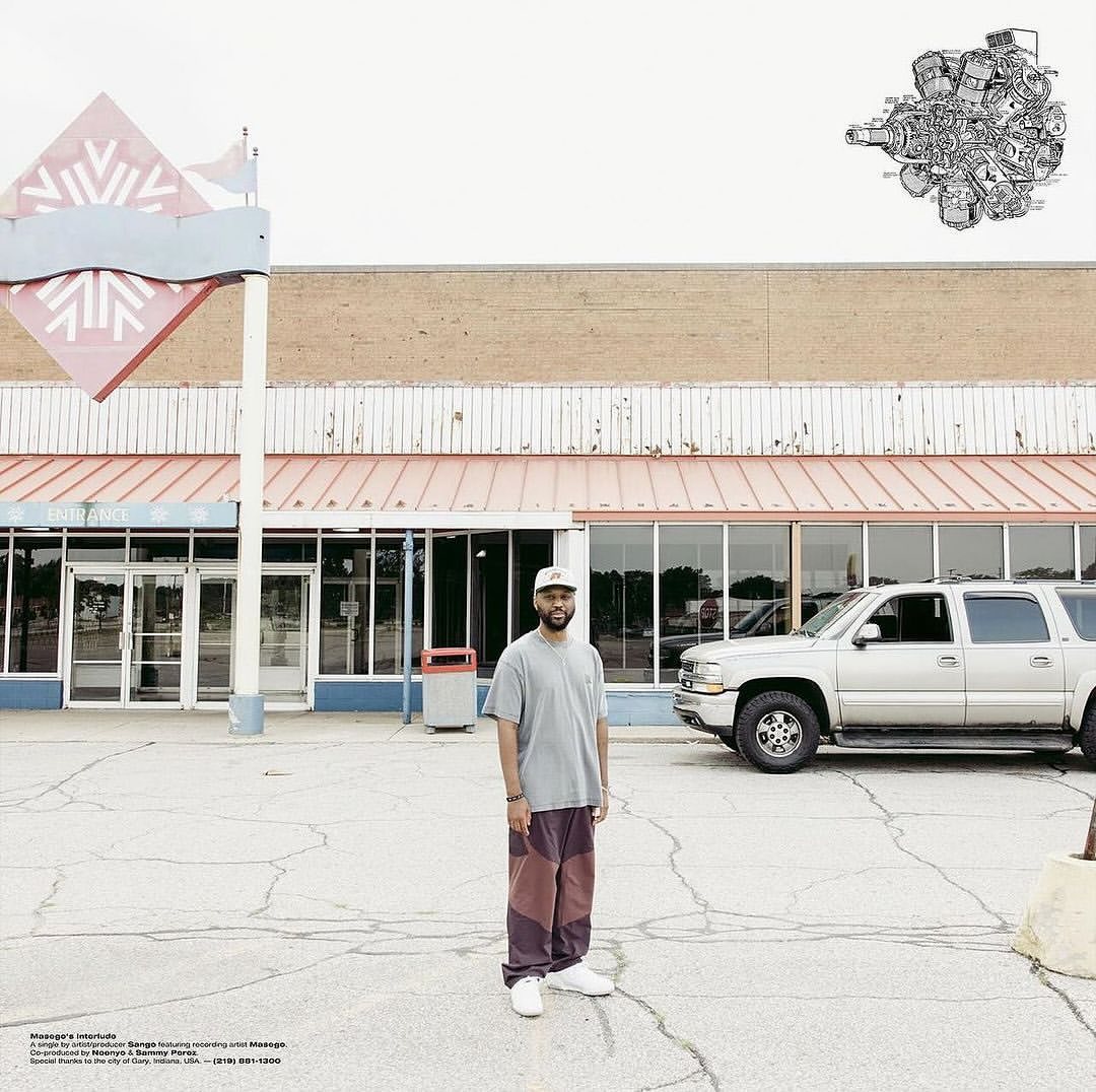 Adult male stands in front of closed retail building in an empty parking lot. A silver SUV is parked in the background.
