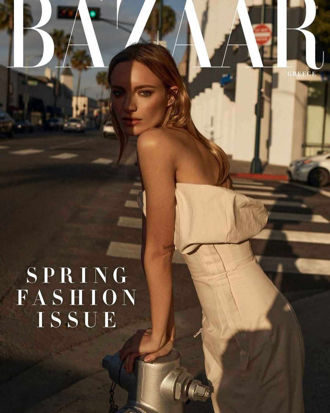 Fashion magazine cover featuring a blond model leaning on a fire hydrant in a city street. Harper's Bazaar masthead is visible.