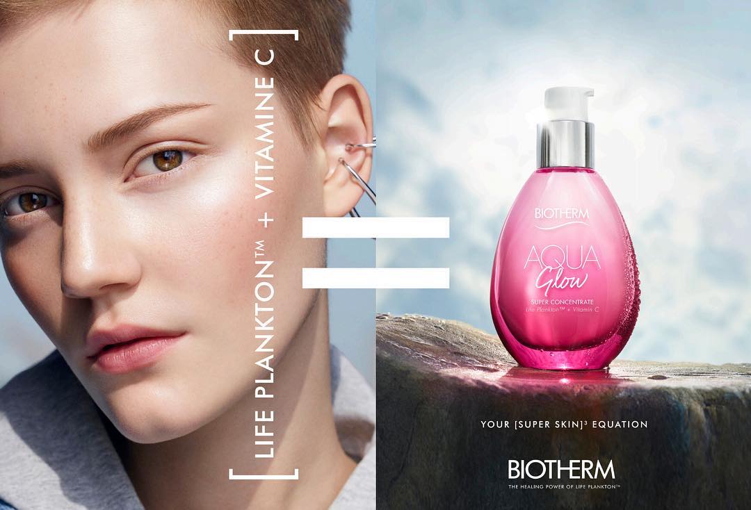 Beauty product advertisement with a pink Biotherm serum bottle, a fair-skinned model, and text for skincare and beauty product promotion.