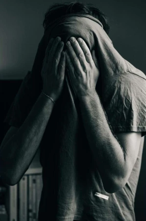 Monochrome portrait of a person pulling a t shirt over their face covering their eyes and hiding from the camera