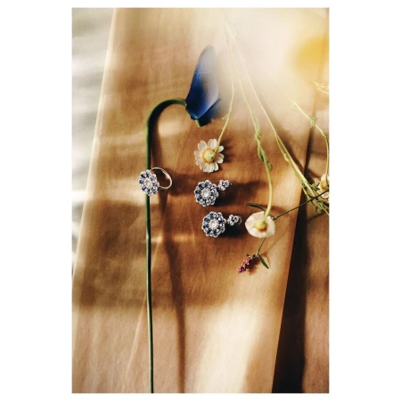 Floral jewelry set featuring a ring and earrings with blue and white stones arranged with fresh daisy and bluebonnet flowers.