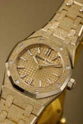 Close-up of a frosted yellow gold Audemars Piguet Mini Royal Oak watch with a textured dial and octagonal bezel.