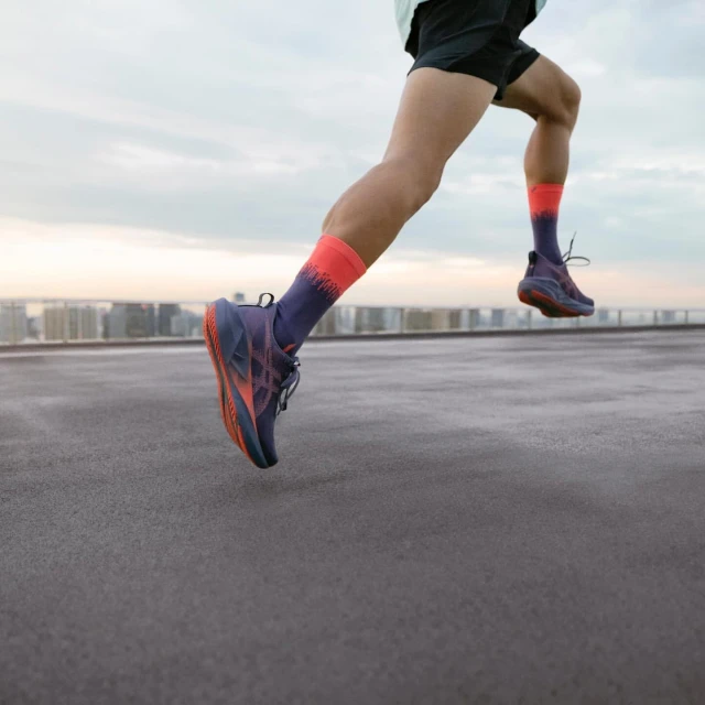 Close-up of a person running outdoors on a rooftop, showcasing athletic shoes and socks against an urban skyline at dusk.