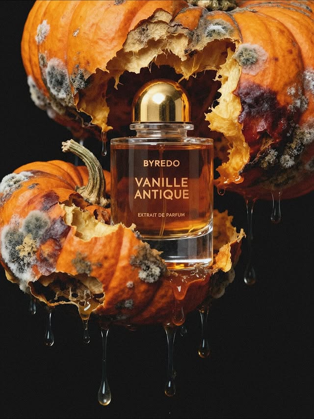 Product shot of Byredo Vanille Antique perfume on decaying pumpkin with dripping fluid against a dark background, emphasizing contrast.