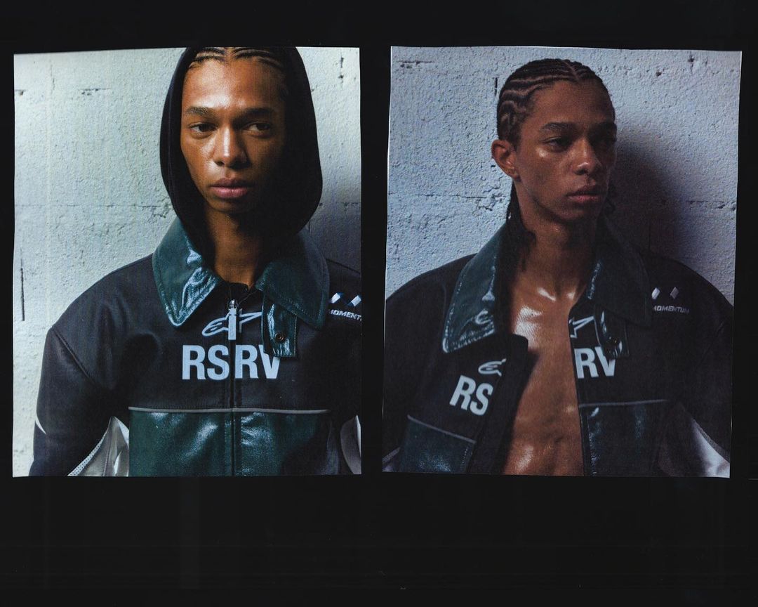 Fashion shot features a young Black male model in a black jacket with a glossy green collar against a textured gray wall for Visie.