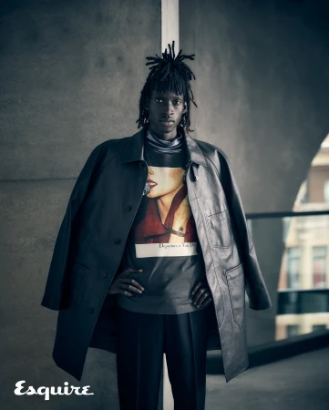 Portrait of a black man with dreadlocks wearing a leather coat and graphic t-shirt photographed by Michele Aboud