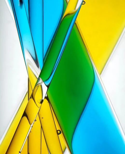 Abstract design featuring intersecting, translucent cylinders filled with bright green, yellow, and blue liquids against a white backdrop.