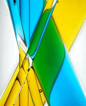 Abstract design featuring intersecting, translucent cylinders filled with bright green, yellow, and blue liquids against a white backdrop.