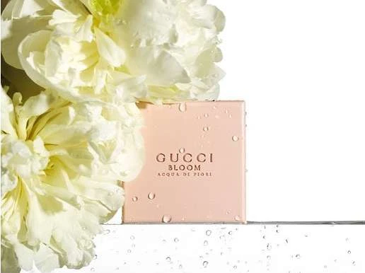 Gucci Bloom Acqua di Fiori perfume product shot with white peonies, showcasing a soft, elegant aesthetic on a white surface.
