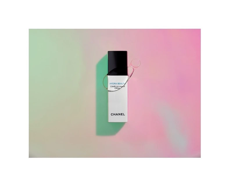 Chanel Hydra Beauty Camellia Water Cream product shot against a soft, diffused pastel background with pinks, greens, and iridescent qualities.