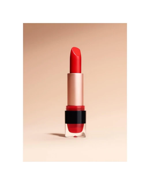 Close-up studio shot of a vibrant red lipstick with a gold tube and transparent base against a soft beige background. Beauty and makeup.