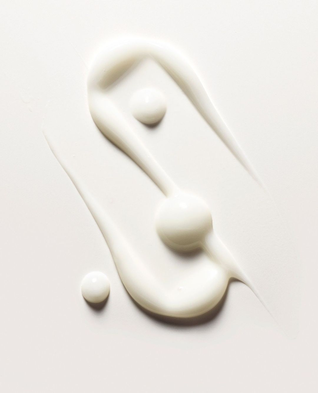 Close-up of swirled skin cream against a white background, showcasing its texture and consistency for beauty and skincare applications.