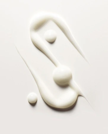 Close-up of swirled skin cream against a white background, showcasing its texture and consistency for beauty and skincare applications.
