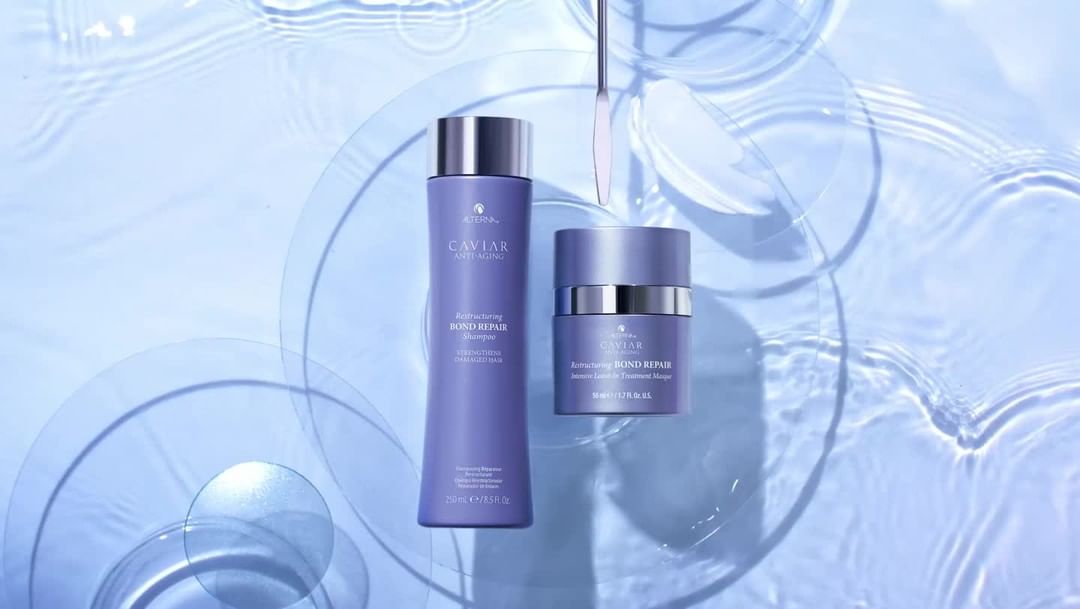 Purple shampoo and conditioner bottles with CAVIAR anti-aging branding are arranged against a background of rippling water patterns.