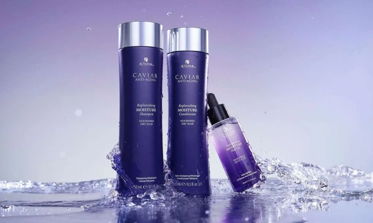 Alterna Caviar anti-aging replenishing moisture shampoo, conditioner and hair oil on a wet surface with water splashing around.