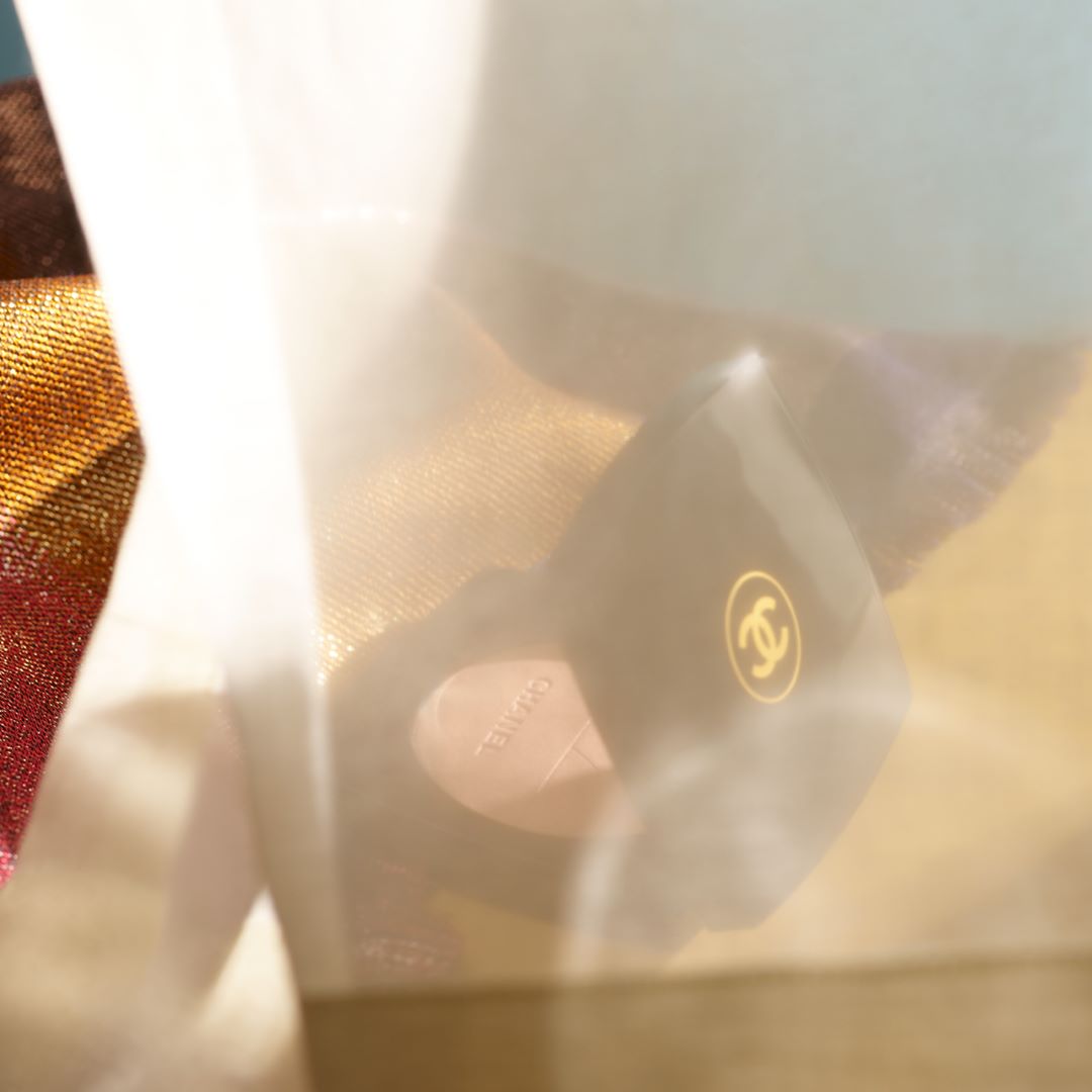 Close-up studio shot of Chanel compact makeup with logo, soft focus, warm light, cosmetic product, luxury brand, beauty.