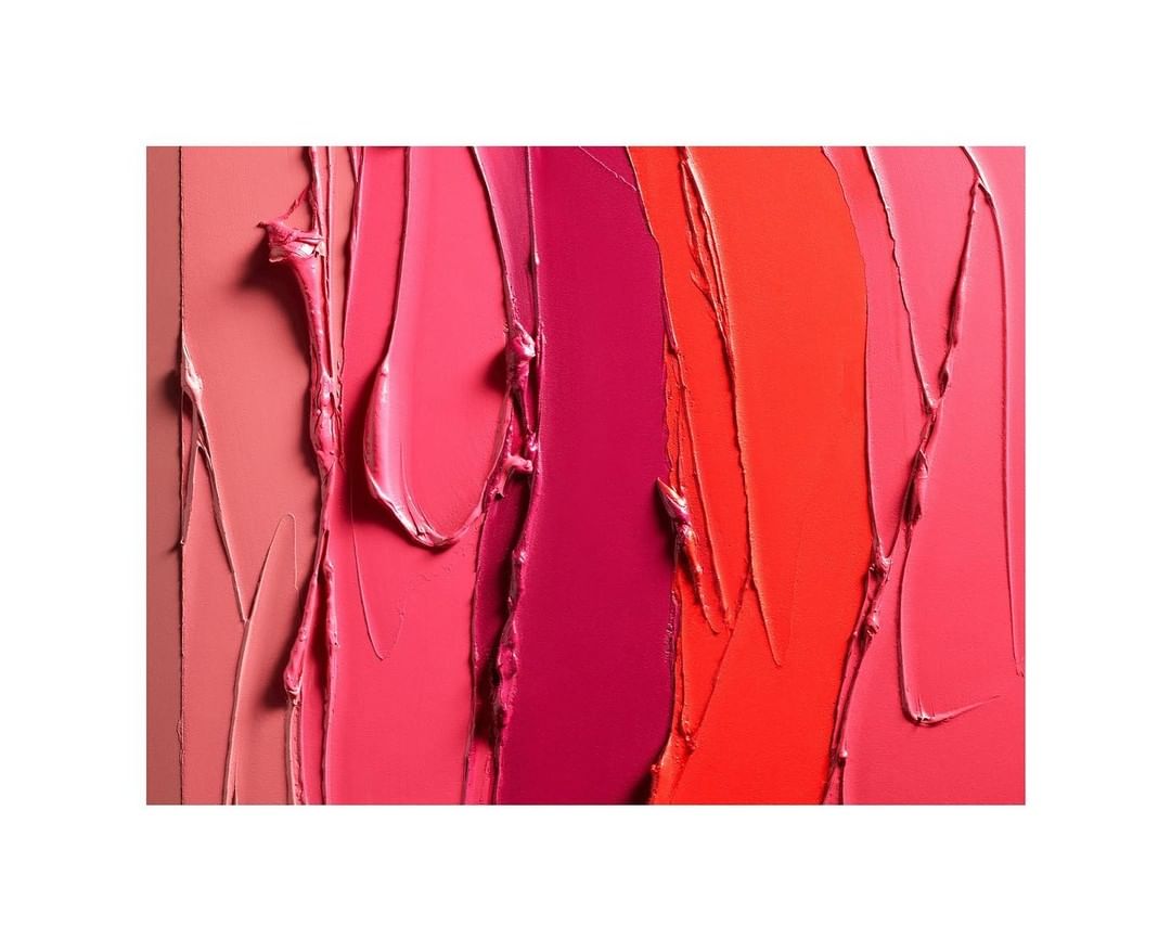 Abstract close-up of cosmetic product swatches with red, pink, and orange creamy textures, and a vertical composition on a white background.