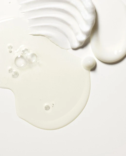Close-up of three distinct textured white creams and gel, including transparent bubbles, against a white background in vertical format.