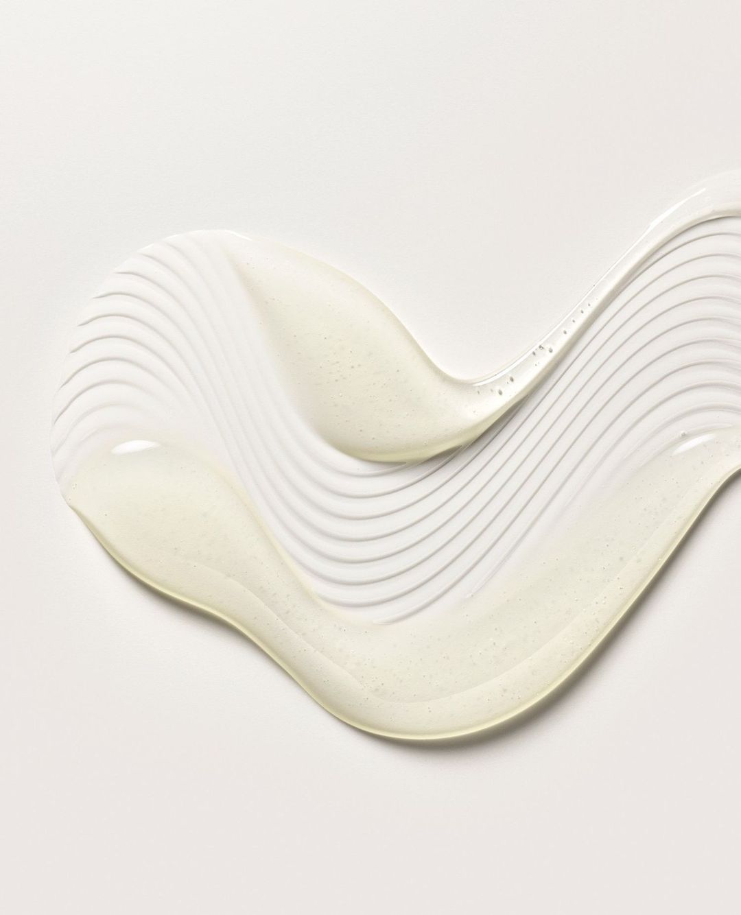 Swirl of pearlescent lotion or cream on white background, ideal for beauty or skincare product demonstration, showing texture.