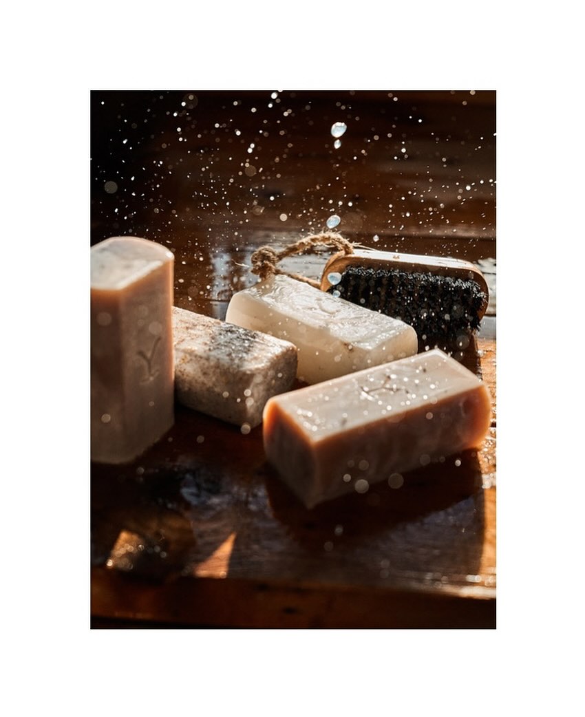 Handmade soaps on a wooden surface with water droplets, highlighting natural skincare and artisan bath products with rustic charm.