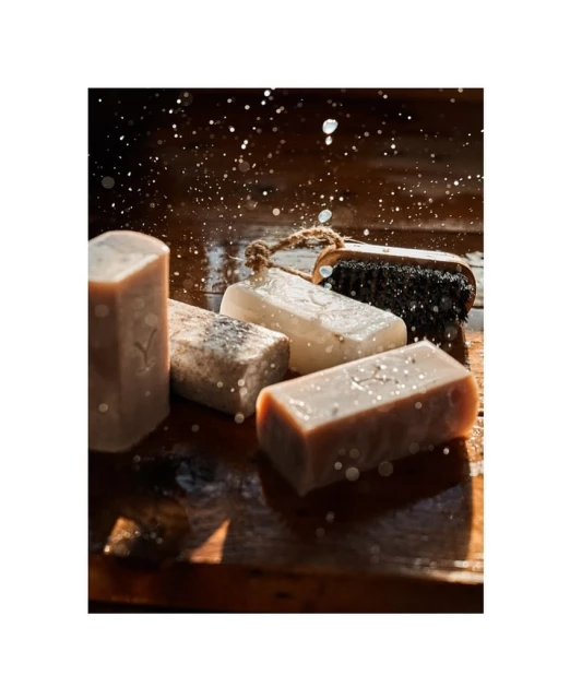 Handmade soaps on a wooden surface with water droplets, highlighting natural skincare and artisan bath products with rustic charm.