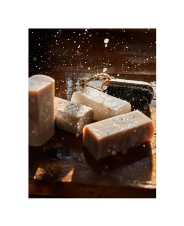 Handmade soaps on a wooden surface with water droplets, highlighting natural skincare and artisan bath products with rustic charm.