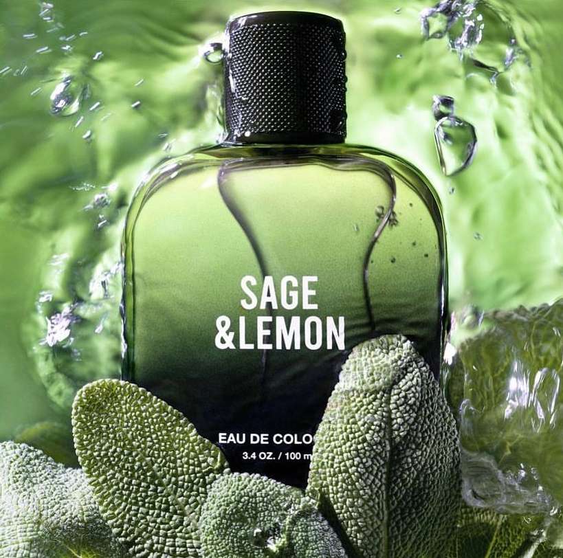 Fragrance bottle of Sage & Lemon Eau de Cologne with water droplets and sage leaves, against a green background.