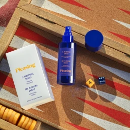 Blue spray bottle and white box with yellow text placed on a backgammon board with dice and checkers.