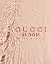 Embossed Gucci Bloom Acqua di Fiori text on a rippling pale pink liquid surface shot from above in Paris by Adam Savitch