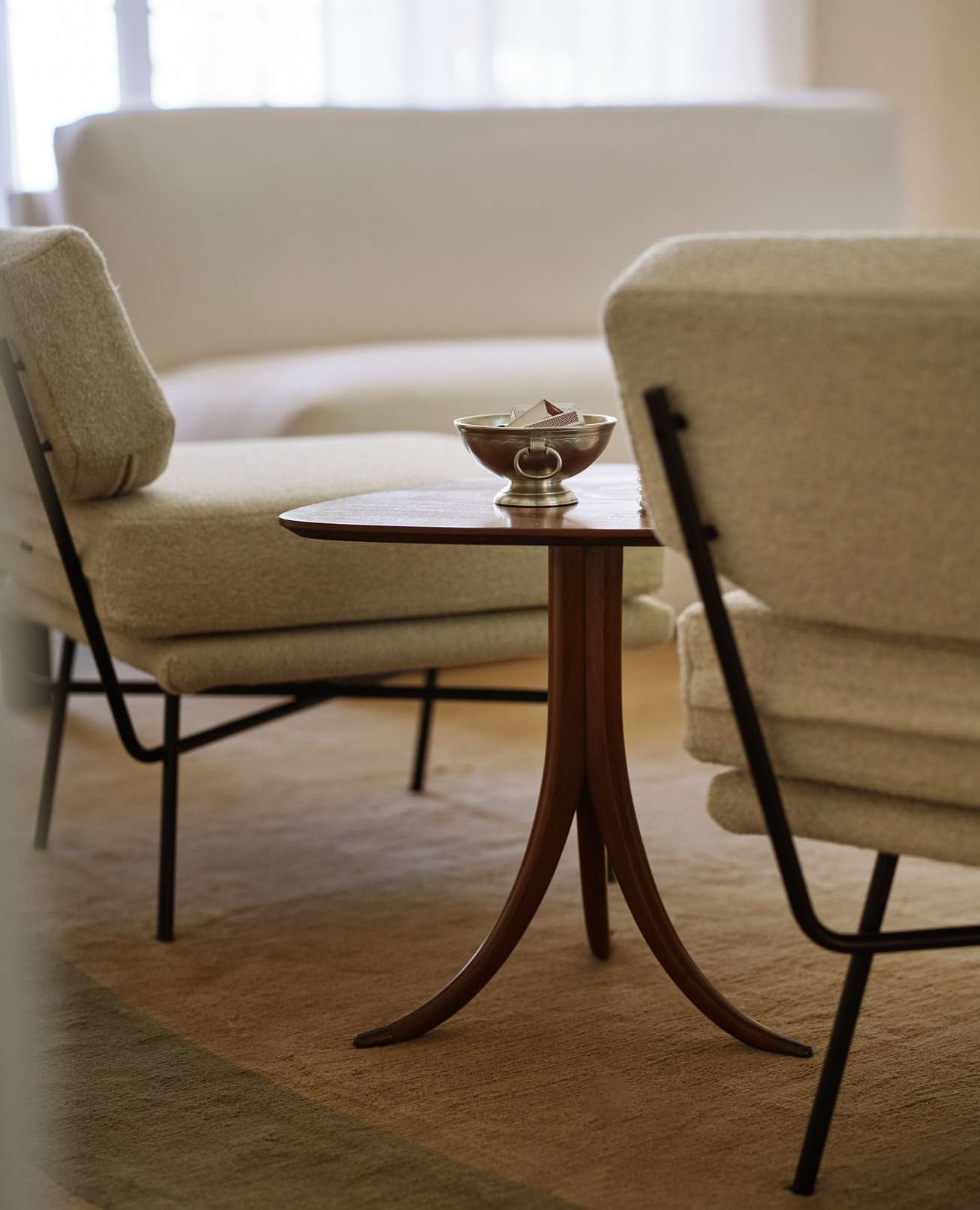 Living room interior featuring modern armchairs and a wooden side table with a metallic bowl, creating a cozy and stylish home environment.