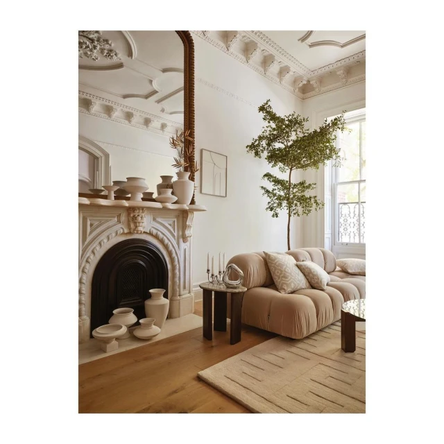 Living room interior with a beige modular sofa, coffee tables, and decorative fireplace with vases in a stylish, neutral-toned space.