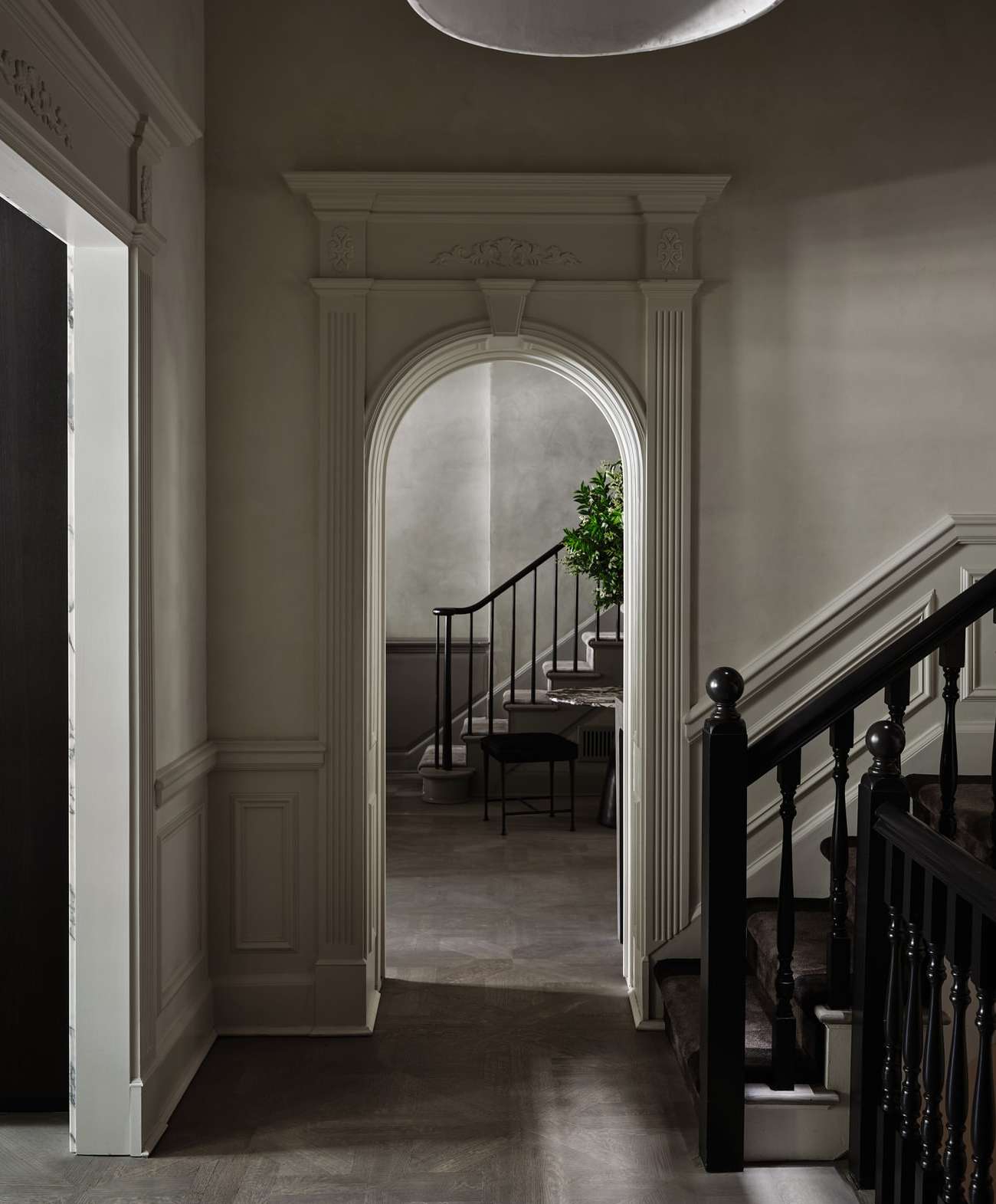 Interior view showcases an arched doorway leading to stairs with black railings and an adjacent doorway in a room with neutral tones.