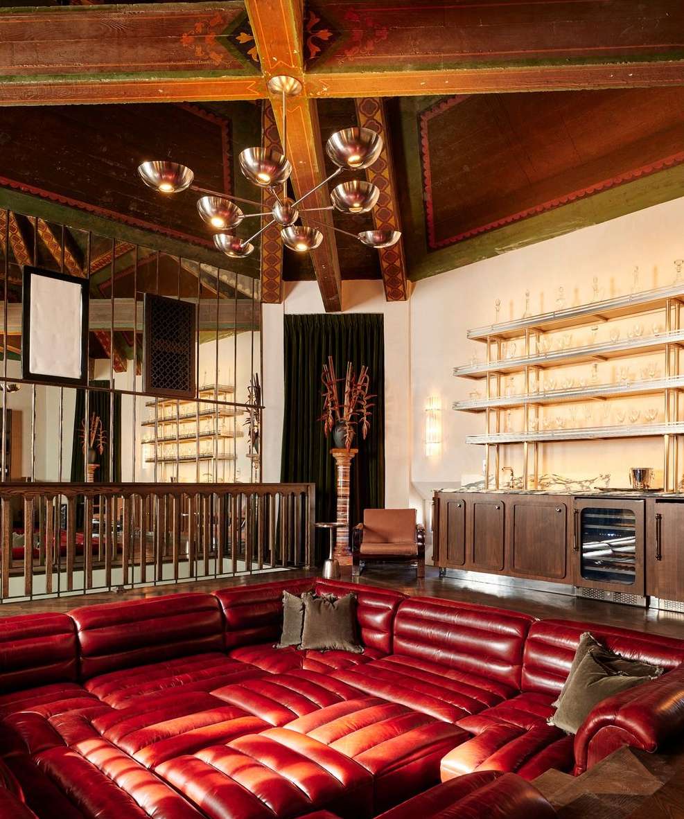 Living room with a sunken red leather couch, a bar area, and ornate ceiling beams, offering a luxurious and unique interior design.