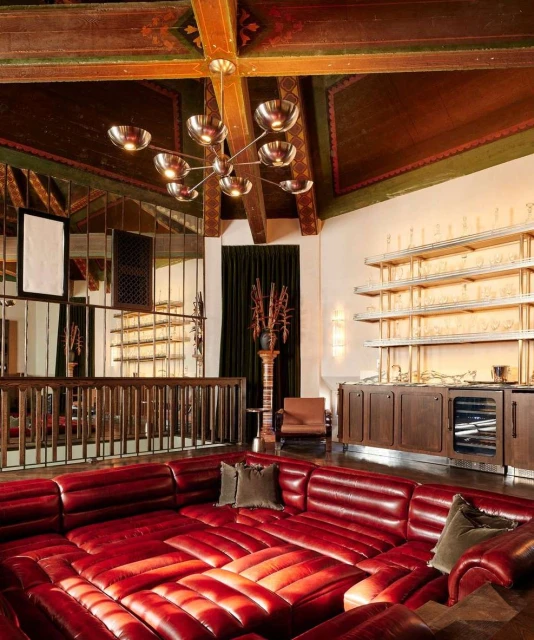 Living room with a sunken red leather couch, a bar area, and ornate ceiling beams, offering a luxurious and unique interior design.