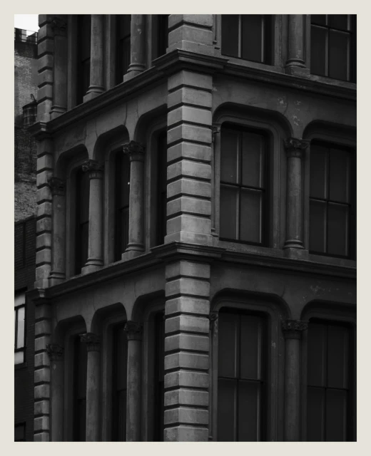 Black and white architectural shot of a building corner with classical features, columns, and windows, showcasing historic urban design.