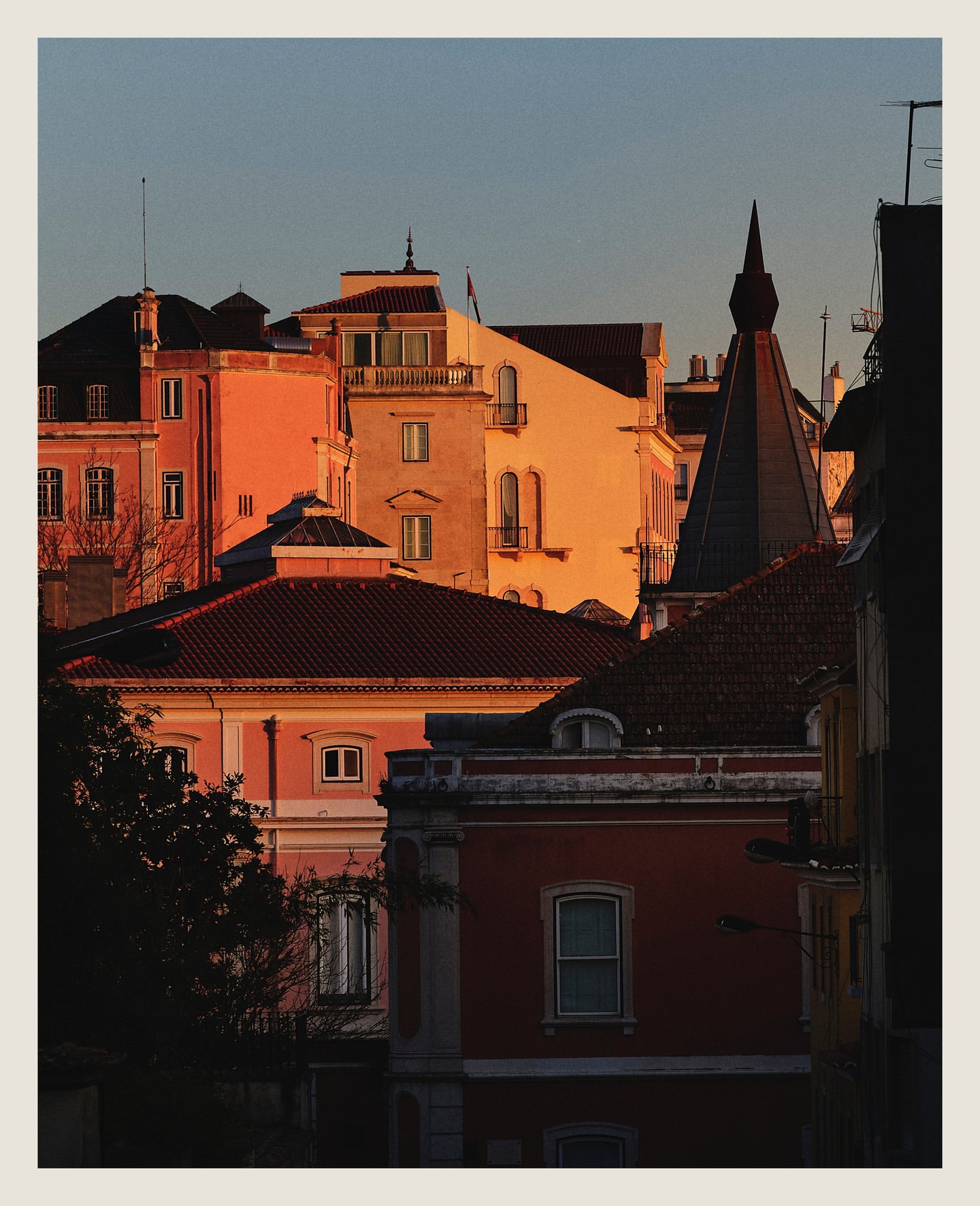 Scenic cityscape featuring buildings with intricate architectural details and warm, vibrant colors during golden hour lighting.