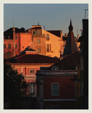 Scenic cityscape featuring buildings with intricate architectural details and warm, vibrant colors during golden hour lighting.