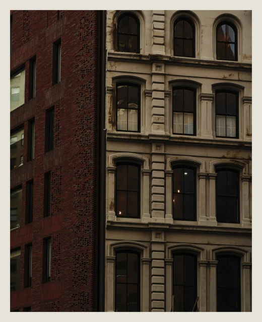 Exterior view of two buildings in an urban environment, one with red brick and the other with a light beige facade, multiple windows.