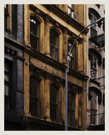 Exterior view of vintage architecture featuring aged facades, tall windows, ornate trim, and urban structural details in daylight.