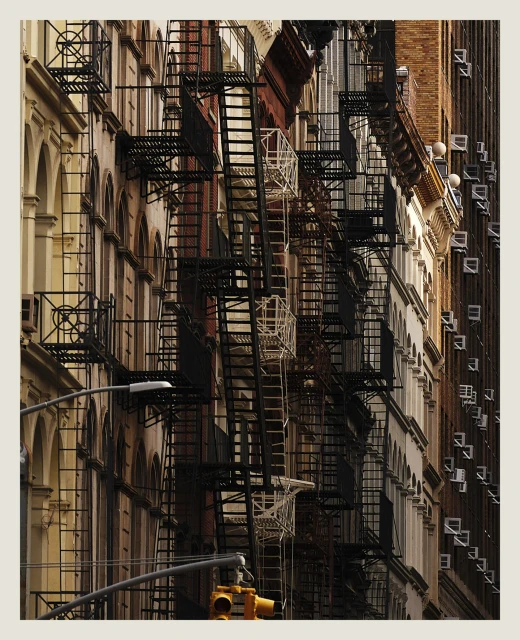 Urban architecture featuring rows of buildings with fire escapes, captured in daytime. The cityscape emphasizes depth and architectural details.