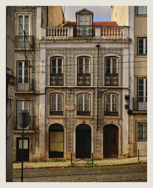 Facade of a multi-story building in Lisbon, Portugal, featuring traditional tilework, windows, and doors on a cobblestone street.