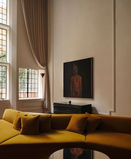 Living room interior featuring a mustard-yellow sectional sofa with pillows, a black accent table, and an art piece above it.