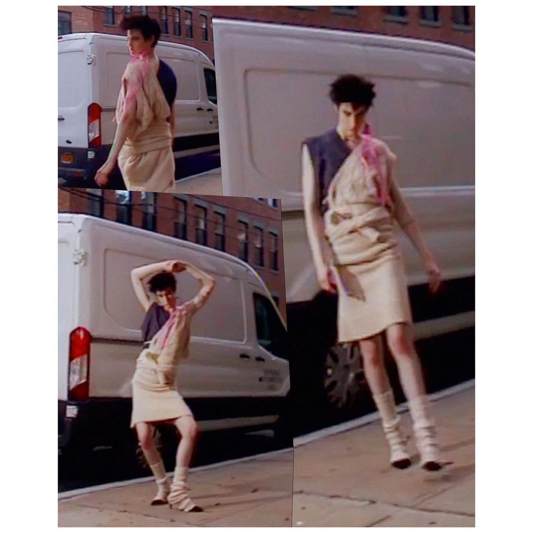 Fashion shot of a person in beige skirt and top with a white van in the background in daylight. Model is posing outdoors.