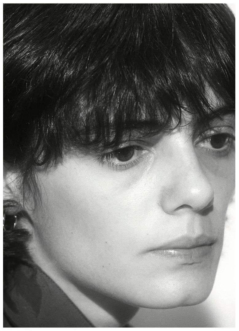 Black and white portrait of a young adult female with short dark hair looking off-camera in a close-up shot, with minimalist composition.