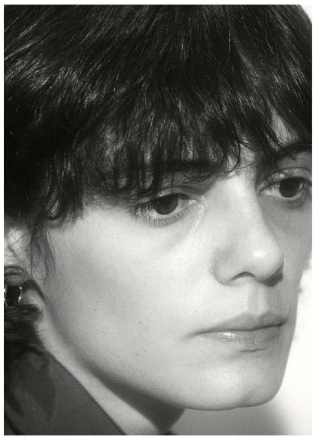 Black and white portrait of a young adult female with short dark hair looking off-camera in a close-up shot, with minimalist composition.