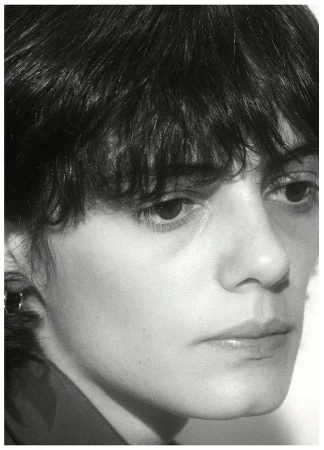 Black and white portrait of a young adult female with short dark hair looking off-camera in a close-up shot, with minimalist composition.