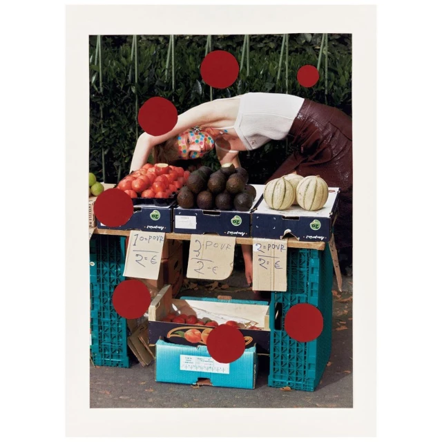 A person with colorful face paint is bending over a market stand filled with fruit against an outdoor, leafy green background.