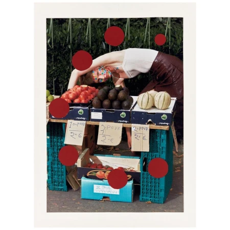 A person with colorful face paint is bending over a market stand filled with fruit against an outdoor, leafy green background.